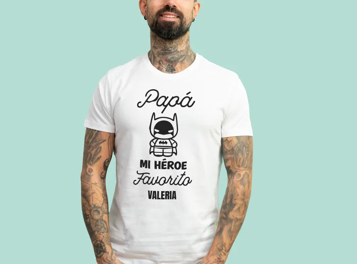 Camiseta blanca con la frase 'Papá, mi héroe favorito', adornada con un dibujo de un superhéroe y personalizada con el nombre que elijas.