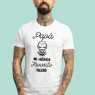Camiseta blanca con la frase 'Papá, mi héroe favorito', adornada con un dibujo de un superhéroe y personalizada con el nombre que elijas.