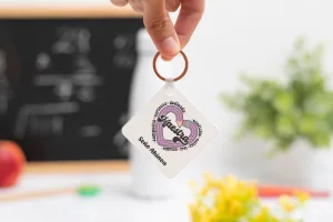 Llavero cuadrado personalizado con el texto Maestra y los adjetivos ‘Comprensiva, cariñosa, dedicada, confiable, cálida, leal y amable', nombre de la profesora, curso y nombres de los niños en el reverso