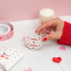 Llavero de enamorados con forma de corazón. Personalizado con nombres y fecha. Fondo con diseño con temática de enamorados de fondo