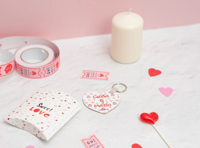 Llavero de enamorados con forma de corazón. Personalizado con nombres y fecha. Fondo con diseño con temática de enamorados de fondo