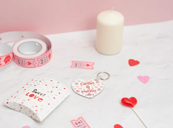 Llavero de enamorados con forma de corazón. Personalizado con nombres y fecha. Fondo con diseño con temática de enamorados de fondo