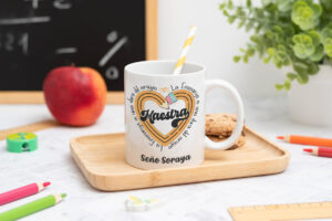 Taza personalizada con el texto ‘Maestra' y ‘La enseñanza es una obra del corazón', nombre de la profesora, curso y nombres de los niños en el reverso
