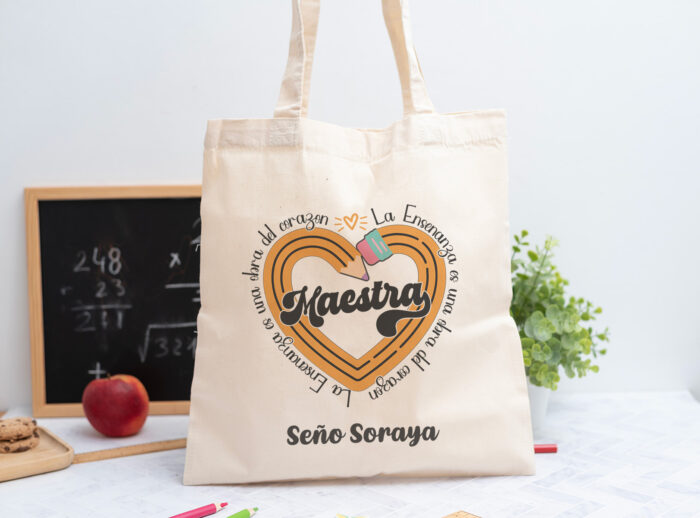 Tote bag personalizada con el texto ‘Maestra' y ‘La enseñanza es una obra del corazón', nombre de la profesora, curso y nombres de los niños en el reverso